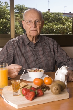 Elderly man eating healthy breakfast.