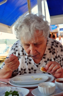 Elderly woman eating dinner.