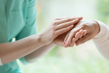 Caregiver holding hands with elderly person.